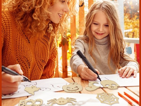 Woman and child painting unfinished wooden Halloween shapes like a skull and spiderweb