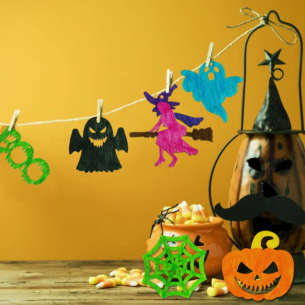 Halloween wooden craft cutouts of ghosts, a witch, and a spiderweb hanging on a string with candy corn and a decorated pumpkin.