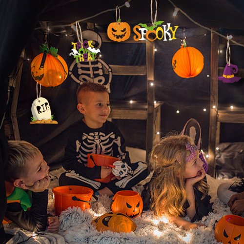 Children in Halloween costumes sitting in a decorated tent with hanging Halloween ornaments.