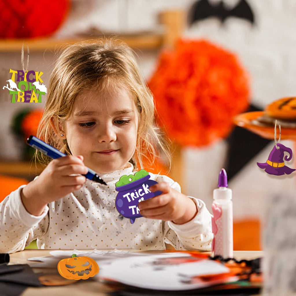 Young girl crafting Halloween ornaments, holding a purple cauldron ornament with 'Trick or Treat' text.
