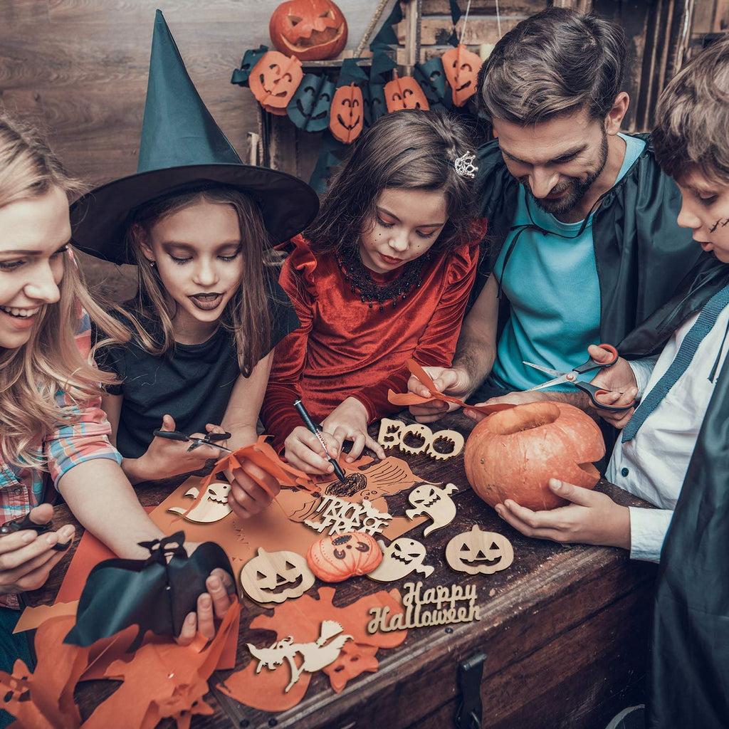 Family crafting Halloween decorations with wooden cutouts and pumpkins on a wooden table.