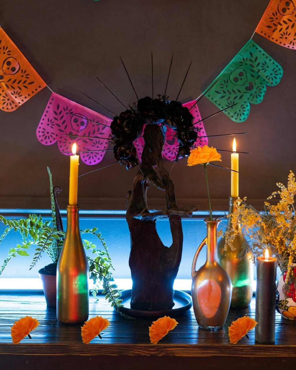 Day of the Dead altar setup with orange marigolds, candles, and papel picado banners