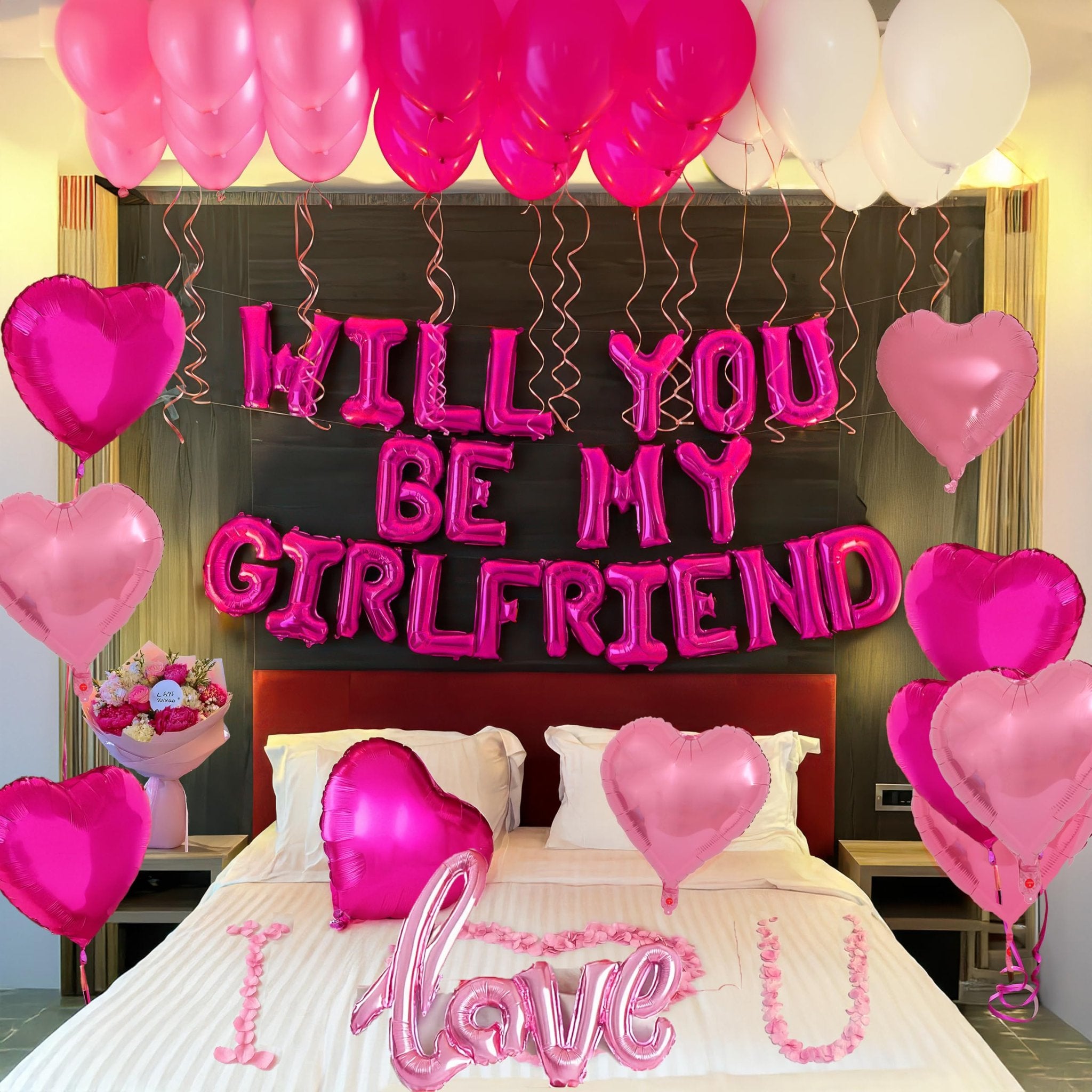 Bedroom decorated with pink and hot pink balloons, including heart shapes and foil letter balloons spelling 'WILL YOU BE MY GIRLFRIEND' and 'I LOVE U'.