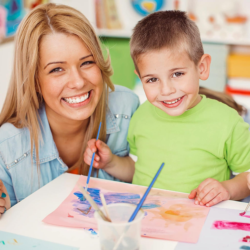Woman and child smiling while painting with small brushes on paper