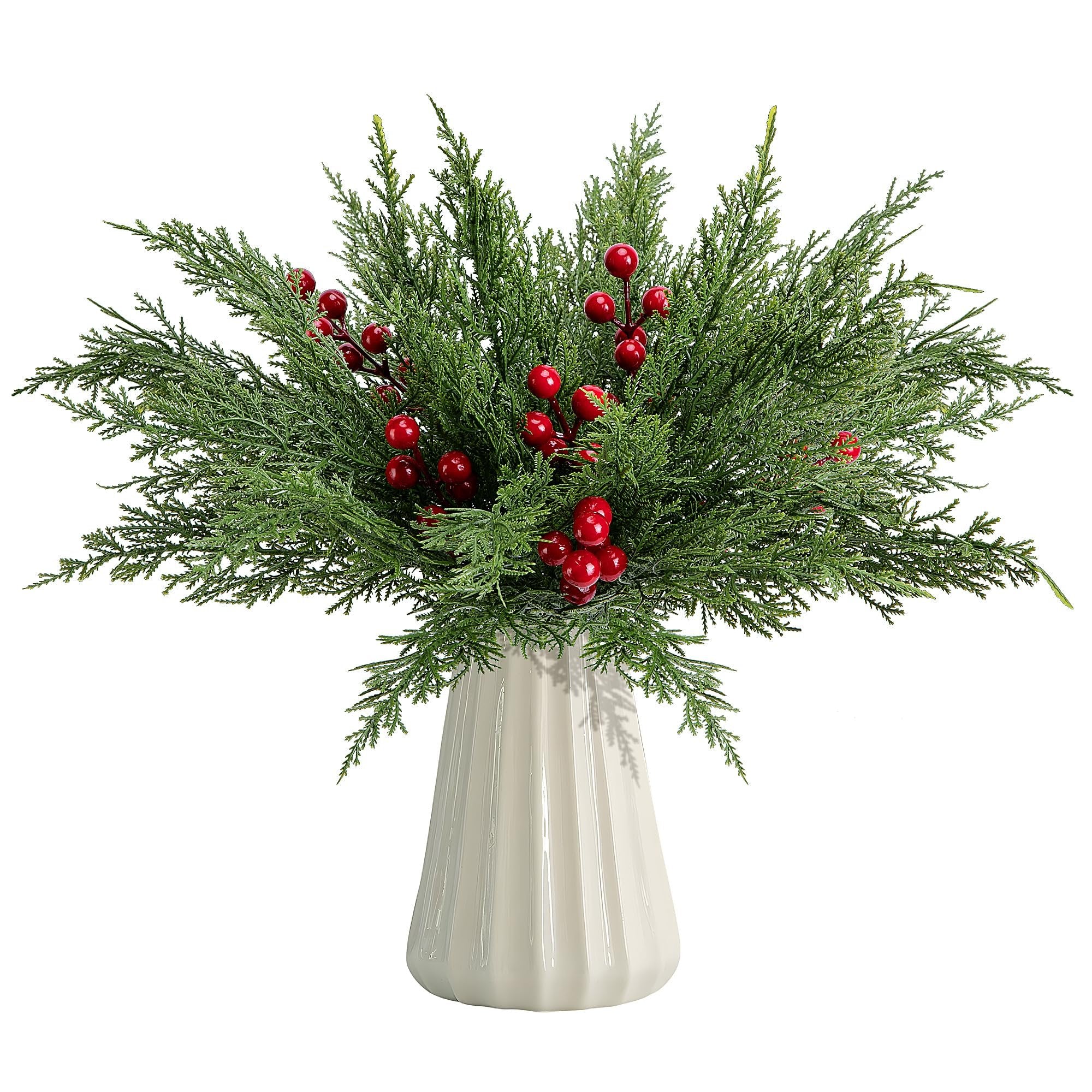 Artificial pine branches with red berries in a white vase, isolated on white background.