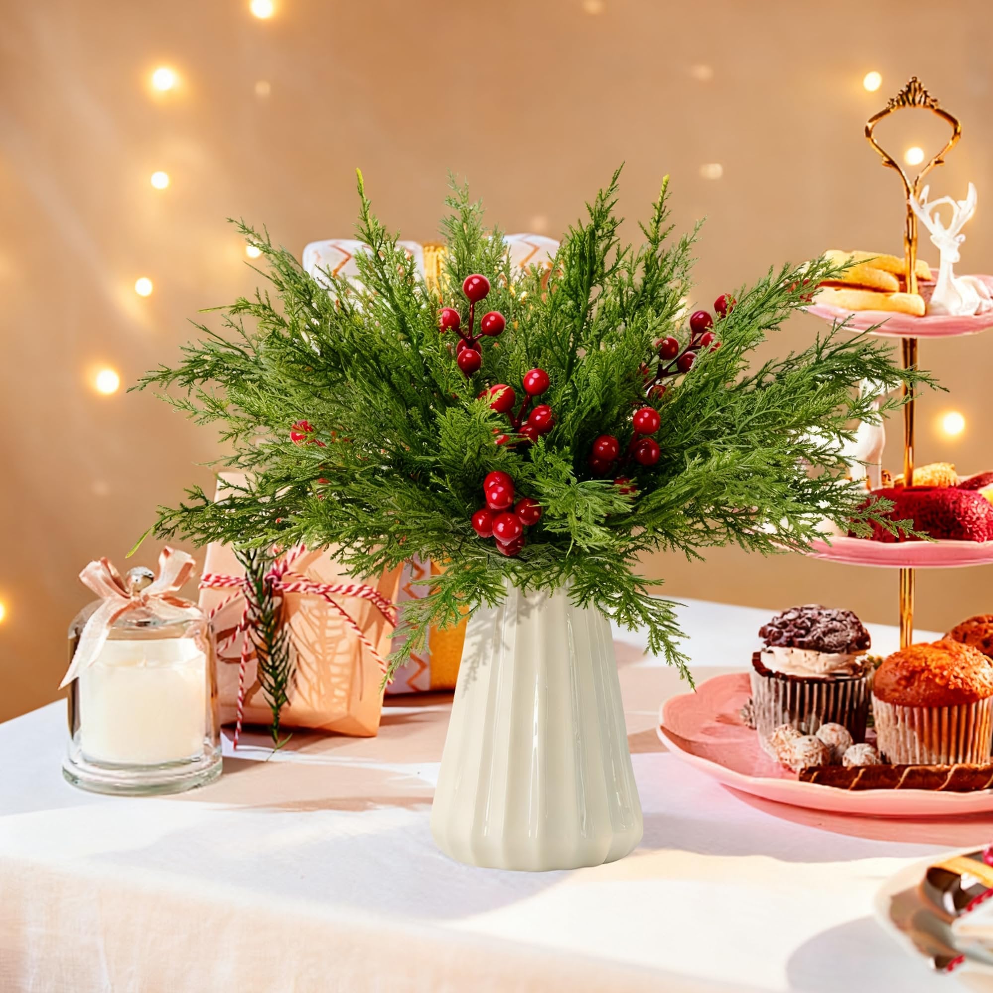 Artificial pine branches with red berries in a vase on a table with gifts and cupcakes