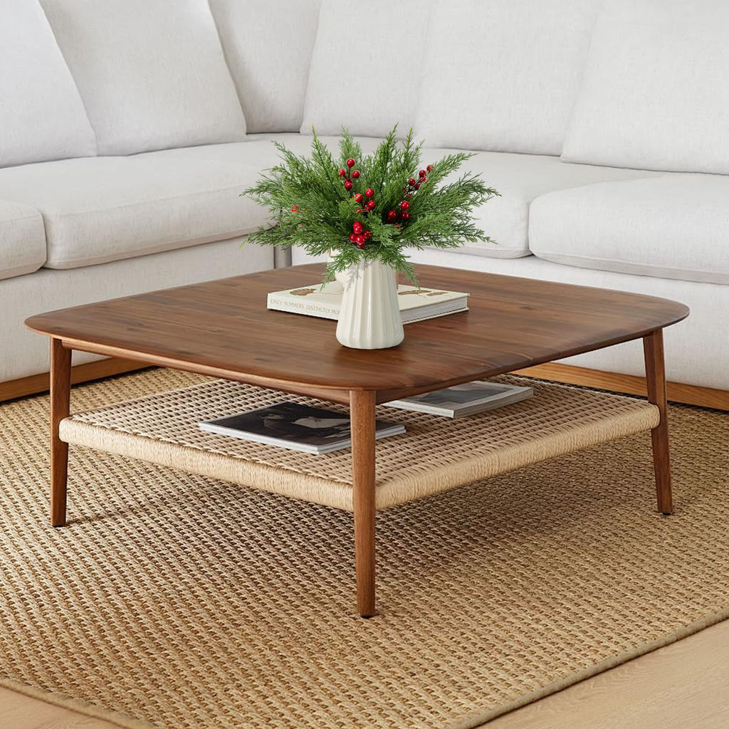 Artificial pine branches with red berries in a vase on a coffee table with books and magazines