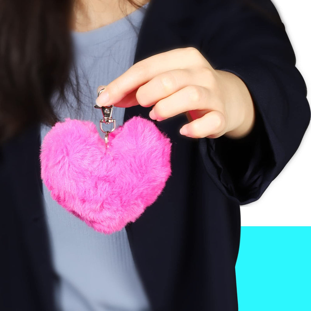 Person holding a fluffy pink heart-shaped keychain with a silver clasp