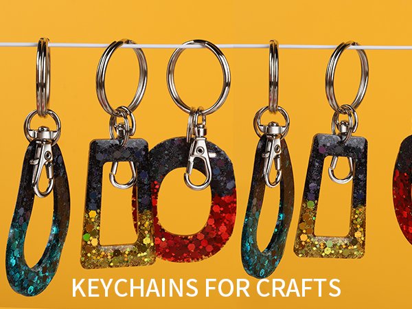 Assortment of glitter-filled resin keychains with silver swivel snap hooks and split rings hanging on a white cord against a yellow background.