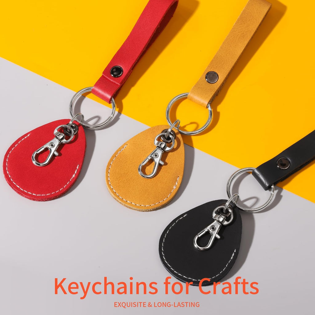 Three leather keychain blanks in red, yellow, and black with silver swivel snap hooks and split rings on a yellow and gray background.