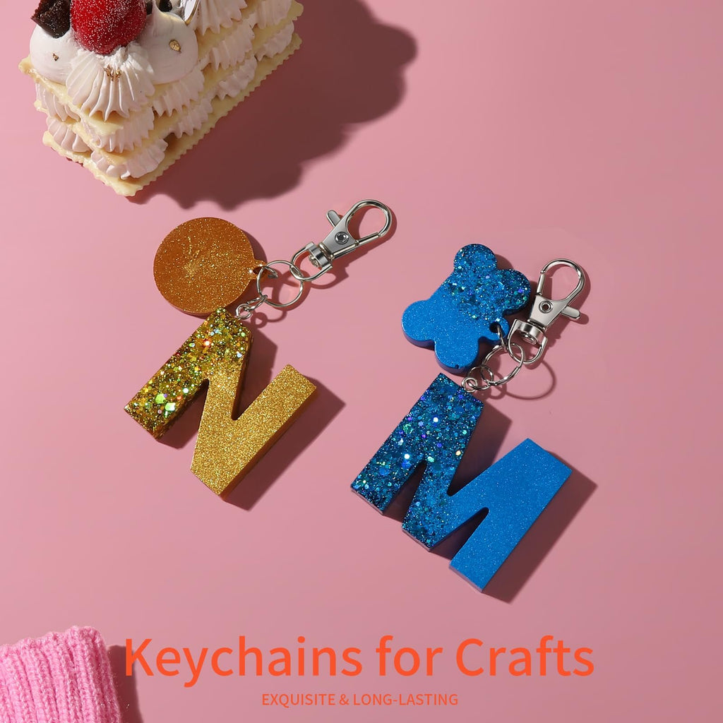 Glitter letter keychains and a slice of cake on a pink background