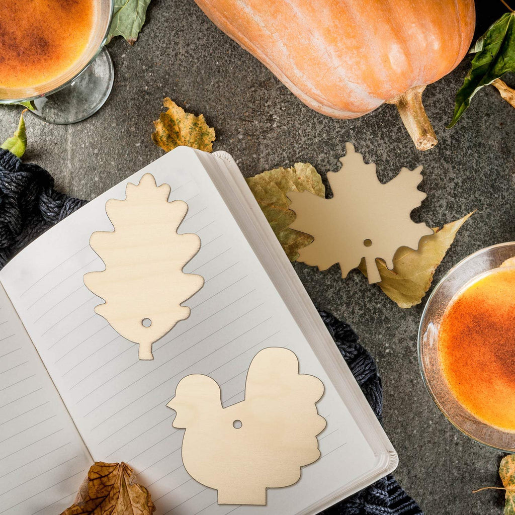 Thanksgiving themed wooden cutouts of a turkey and oak leaf on an open notebook, surrounded by autumn leaves and a pumpkin.