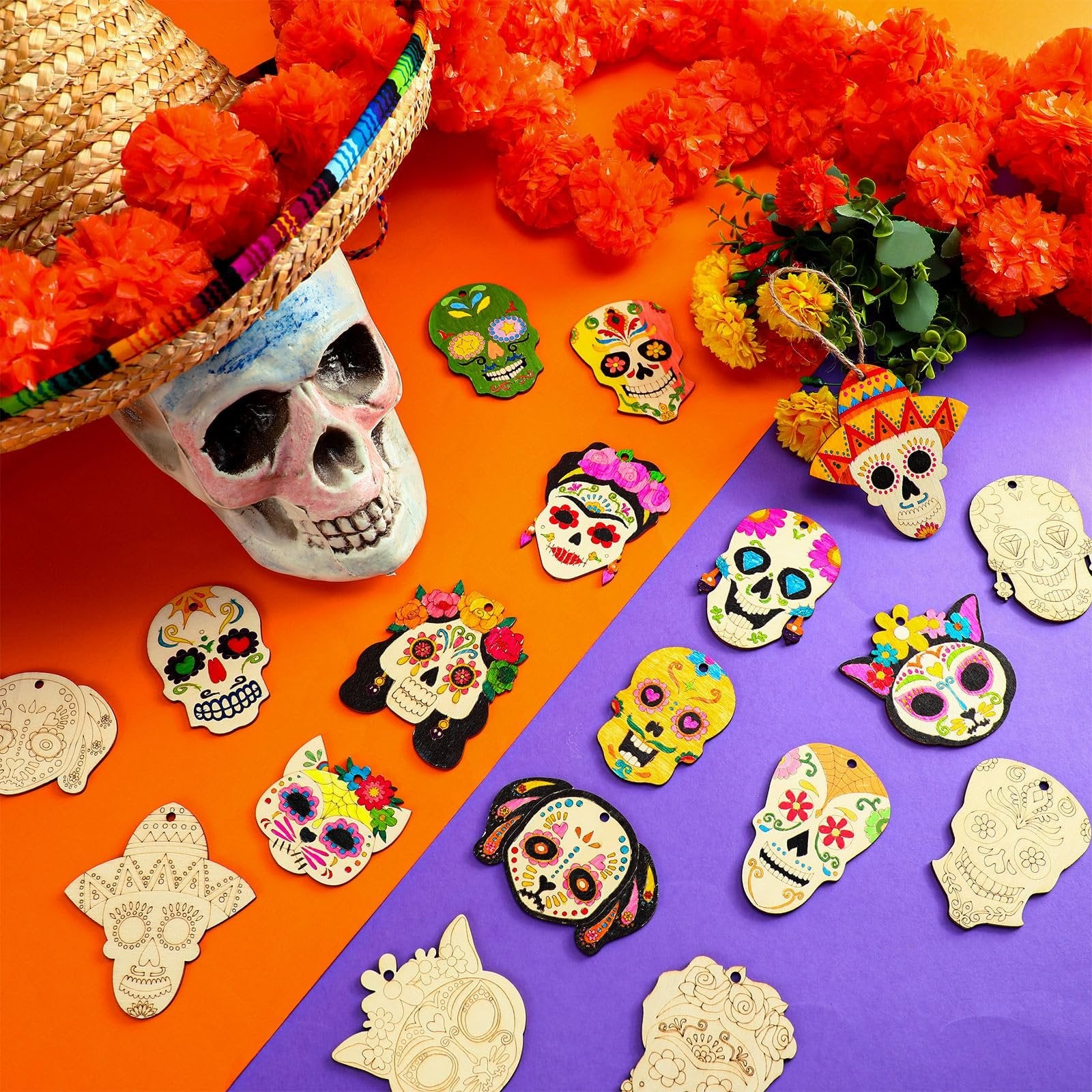 Unfinished wooden sugar skull ornaments and decorative skulls arranged with a sombrero and marigold garland on an orange and purple background.