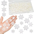 White glitter resin snowflakes in three sizes displayed on a hand and scattered around a clear storage box.