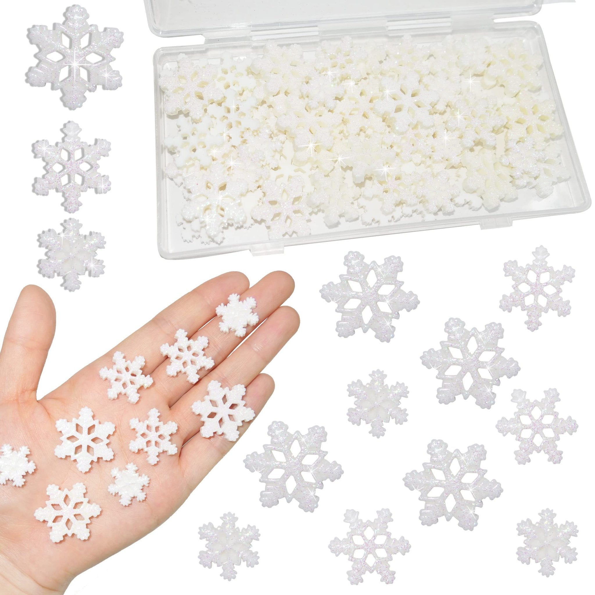 White glitter resin snowflakes in three sizes displayed on a hand and scattered around a clear storage box.