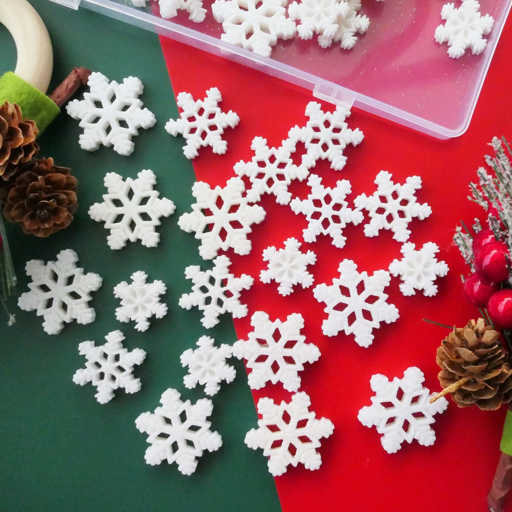 White glitter resin snowflakes scattered on a red and green background with pinecones and festive berries.