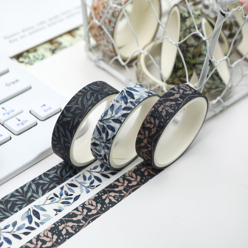 Three rolls of floral and leaf patterned washi tape on a white surface next to a keyboard.