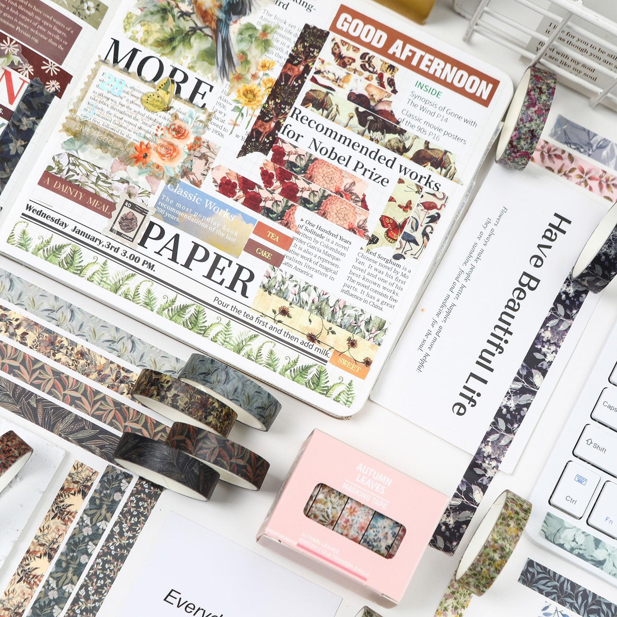 Assortment of floral and leaf patterned washi tapes laid out on a surface with decorative paper and a keyboard.