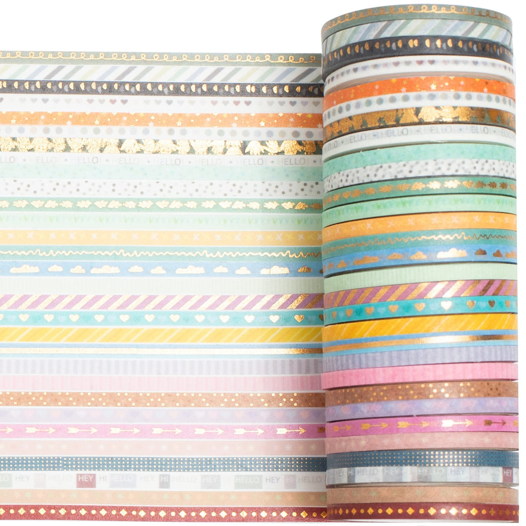 Roll of skinny gold foil washi tape with various patterns and a stack of individual rolls, close-up view.