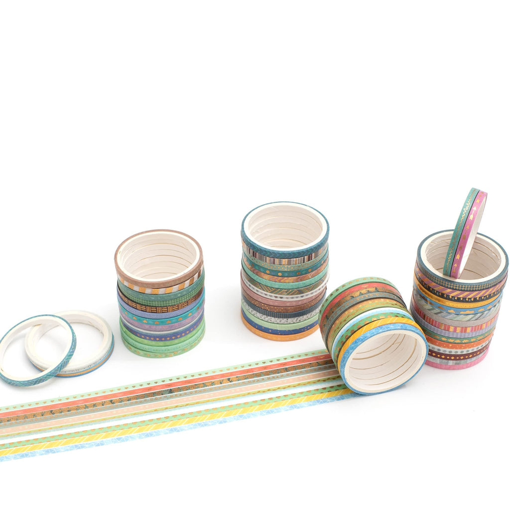 Stacks of skinny gold foil washi tape rolls with various patterns, some unrolled on a white background.