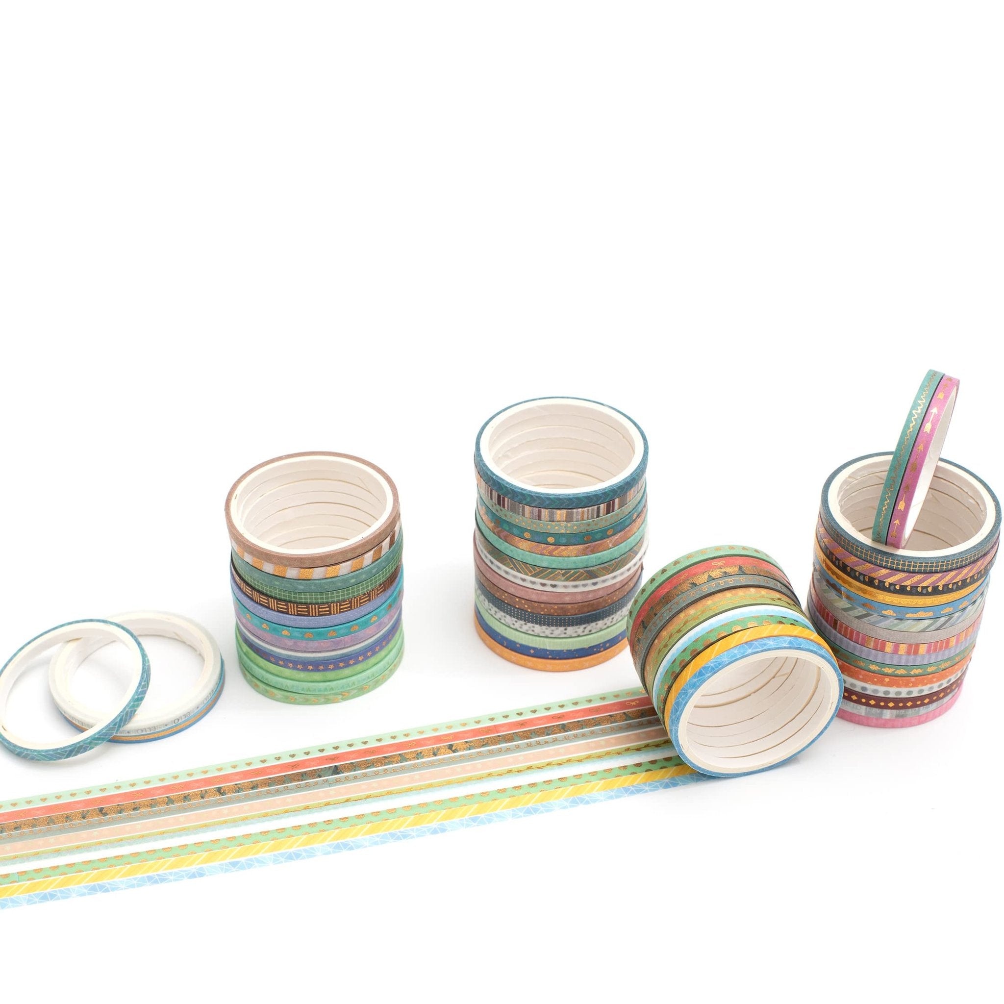 Stacks of skinny gold foil washi tape rolls with various patterns, some unrolled on a white background.