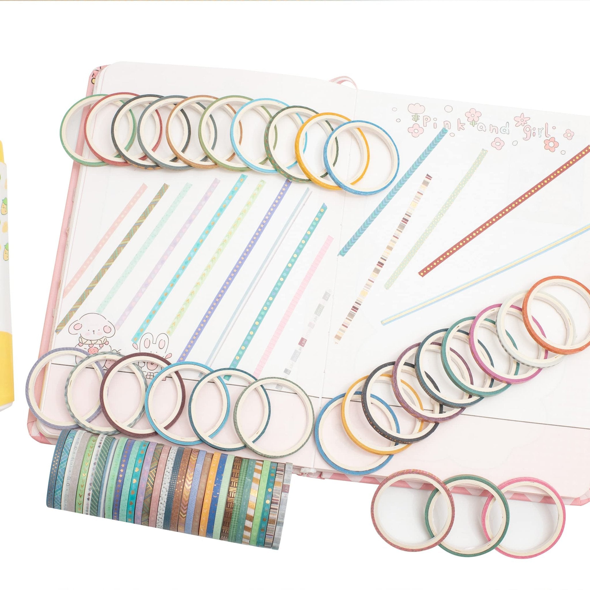 Assortment of skinny gold foil washi tapes arranged on an open journal with decorative lines and cartoon animals.