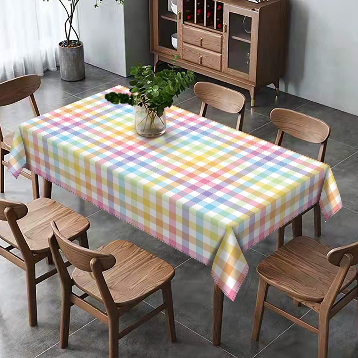 Rectangular tablecloth with pastel buffalo check plaid pattern draped over a dining table with chairs.