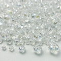 Pile of clear faceted rondelle glass beads in various sizes on a white surface