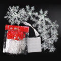 White glittery snowflake ornaments with string and double-sided tape on a black background