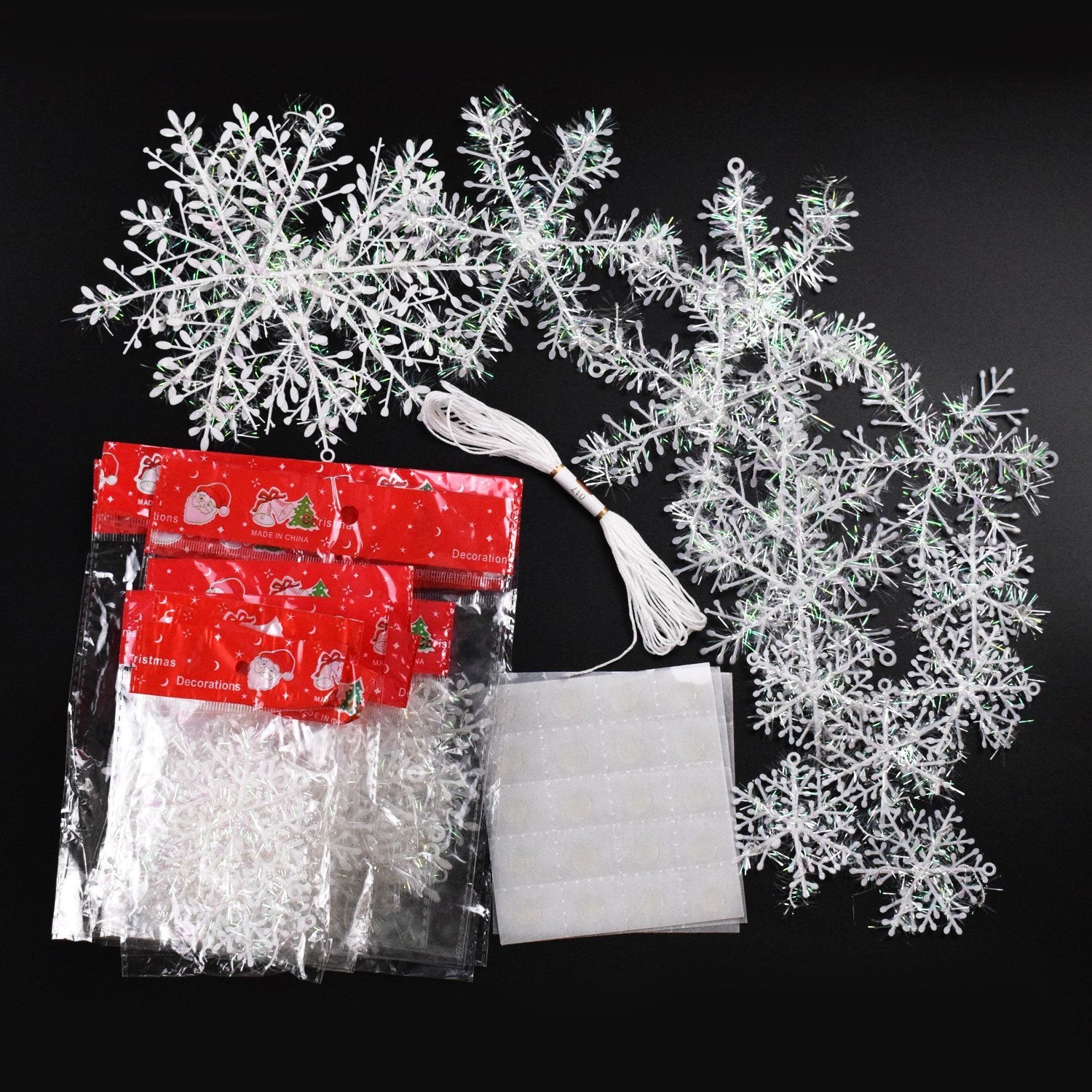 White glittery snowflake ornaments with string and double-sided tape on a black background