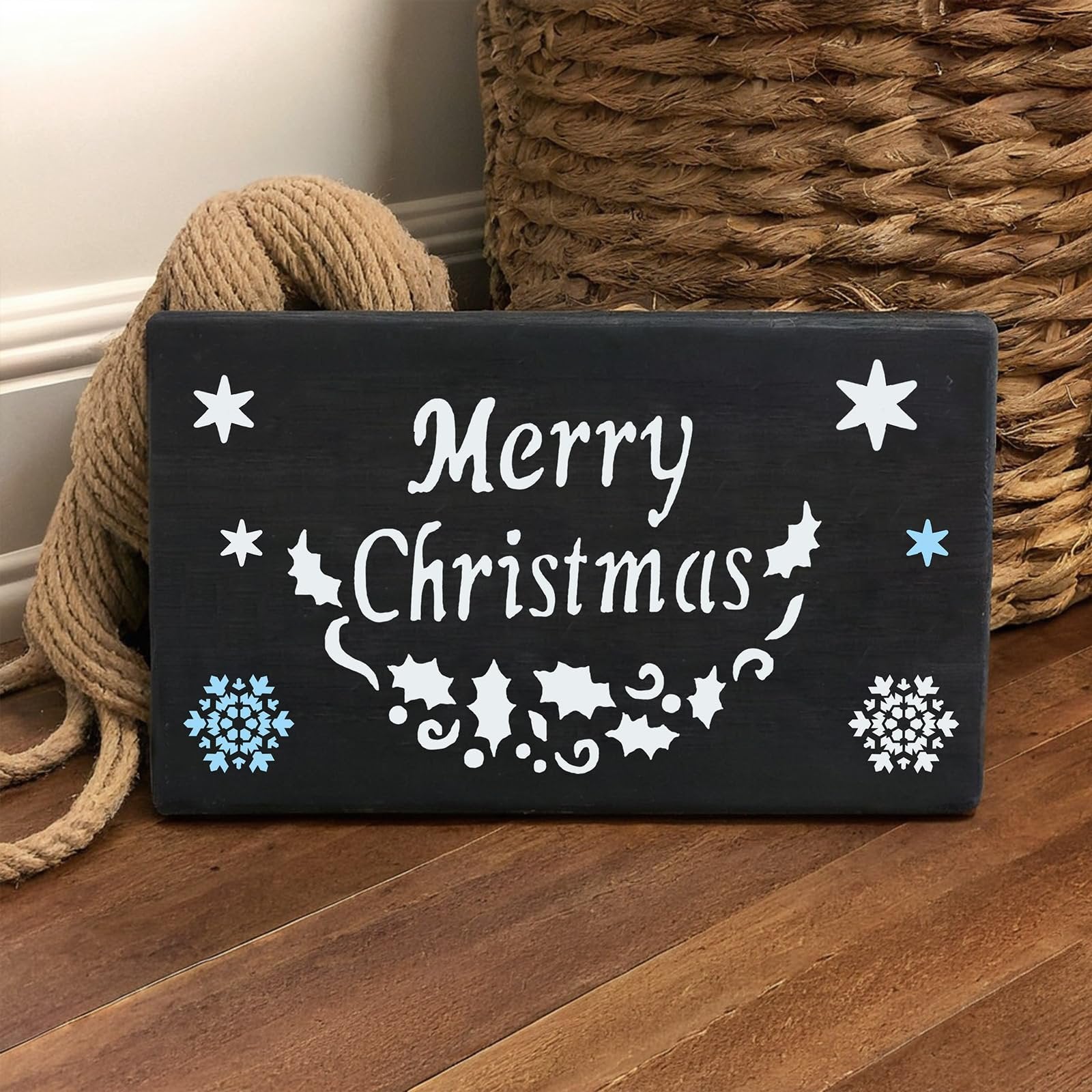 Black wooden sign with 'Merry Christmas' text and festive holiday designs, including snowflakes and holly leaves.