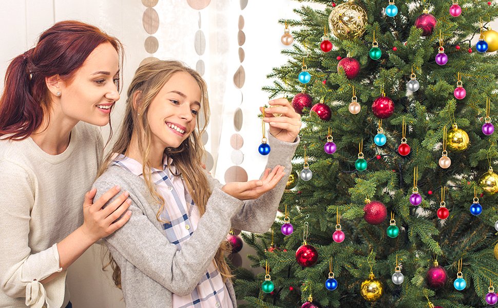Mother and daughter decorating a Christmas tree with colorful mini ornaments