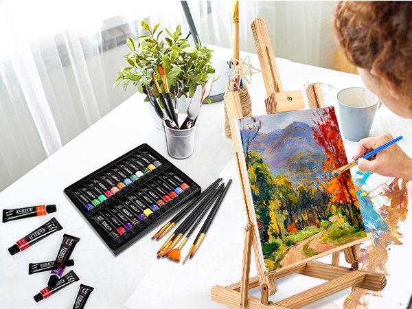 Acrylic painting set with paint tubes, brushes, easel, and canvas being painted by a person.