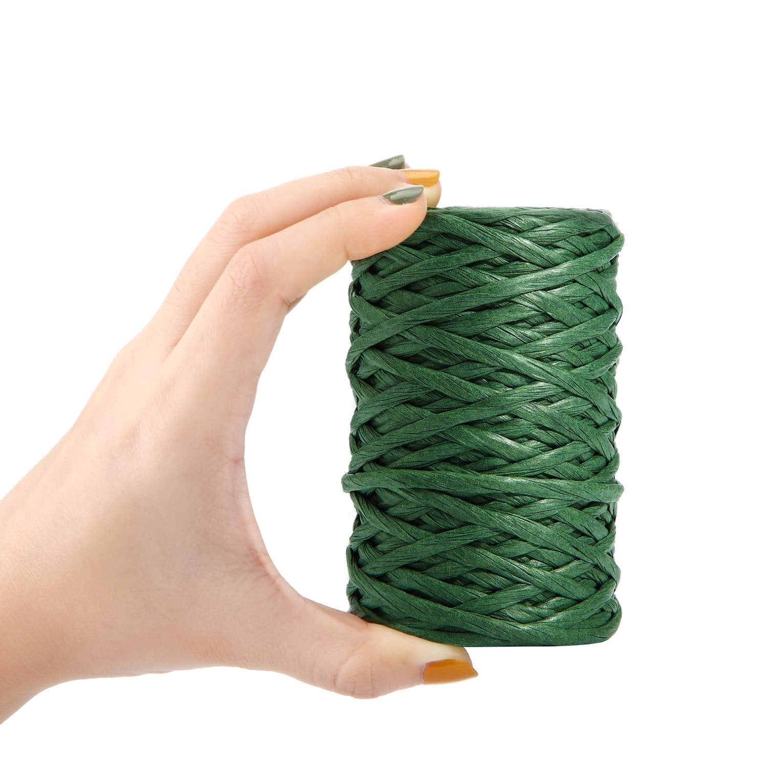 Hand holding a roll of dark green floral bind wire on a white background.