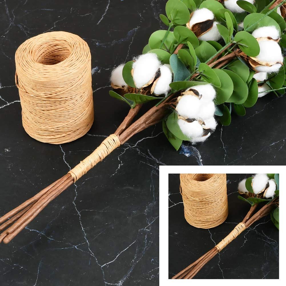 Roll of khaki floral bind wire next to a bouquet of artificial eucalyptus and cotton stems on a black marble background.
