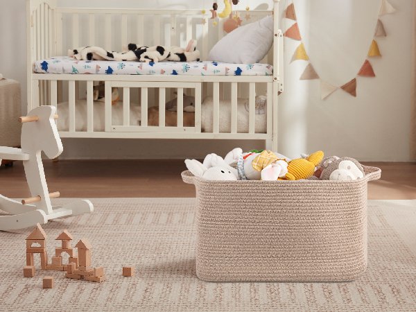 Large woven storage basket filled with stuffed toys in a nursery setting with a crib and rocking horse