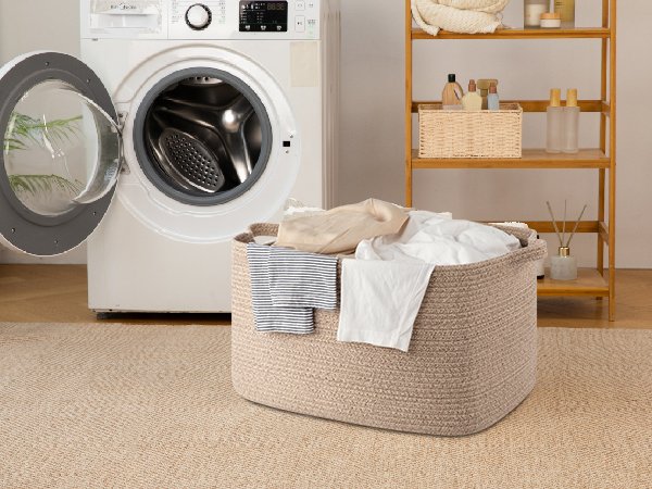 Large woven rope basket filled with laundry next to a washing machine