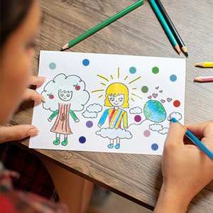 Child's drawing of two people and the Earth, decorated with colorful dot stickers, with colored pencils nearby.