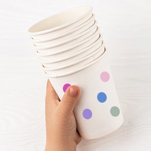 Hand holding a stack of white paper cups with colorful polka dot pattern