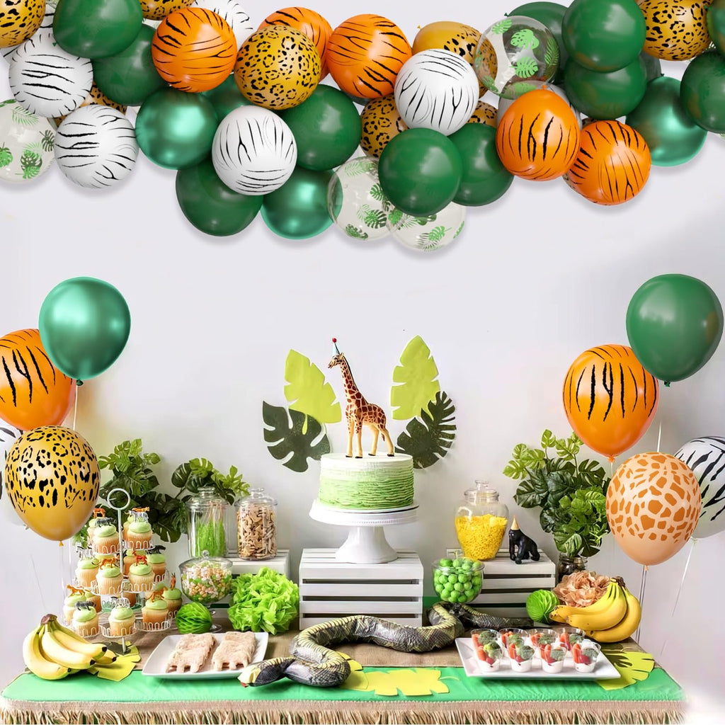 Jungle safari themed party table with animal print balloons, cupcakes, cake, and snacks.