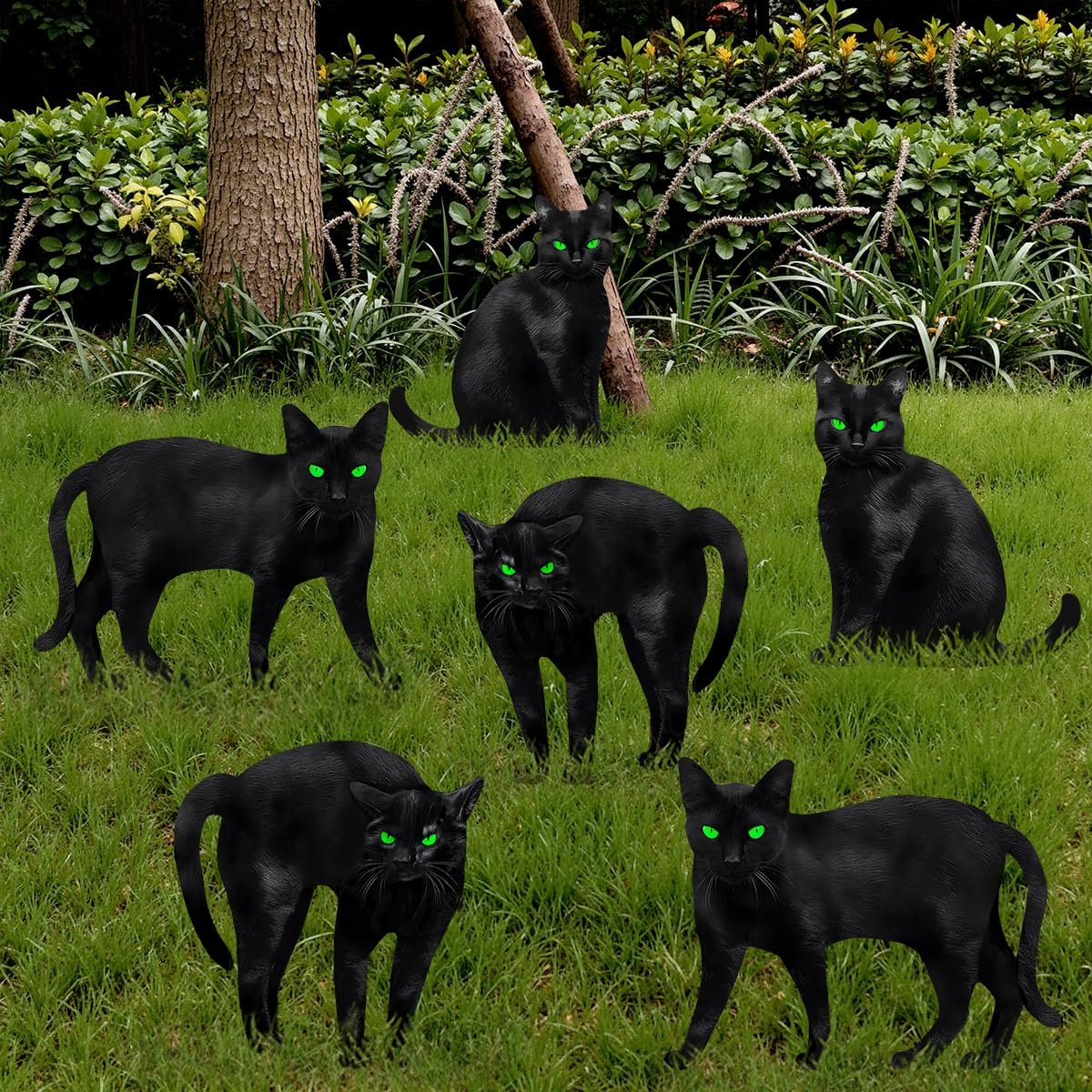 Six black cat silhouette yard signs with glowing green eyes arranged on a grassy lawn with trees and bushes in the background.