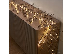 Brown twig garland with 120 warm white fairy lights draped on a ribbed wooden surface.