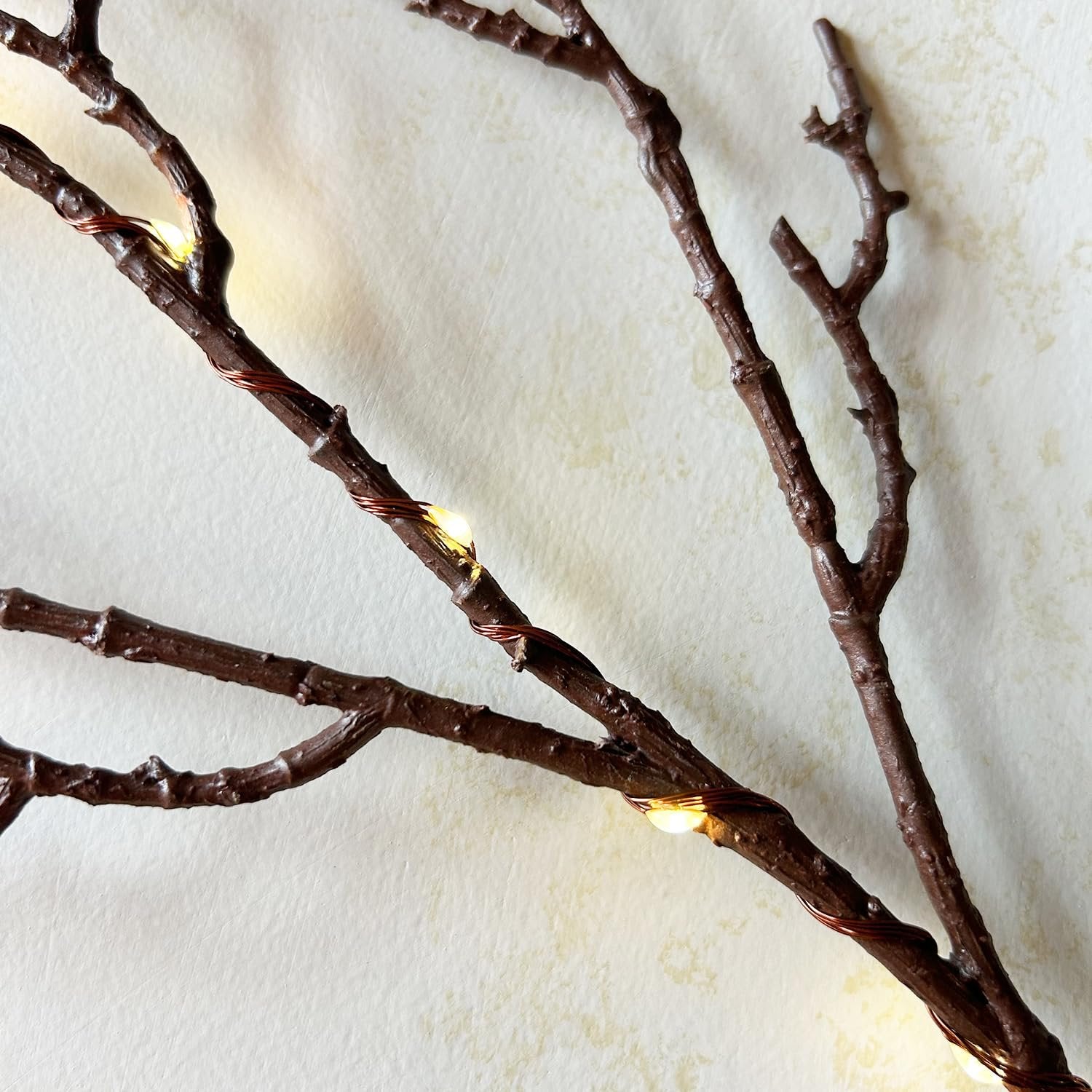Brown twig garland with warm white fairy lights wrapped around branches, close-up view.