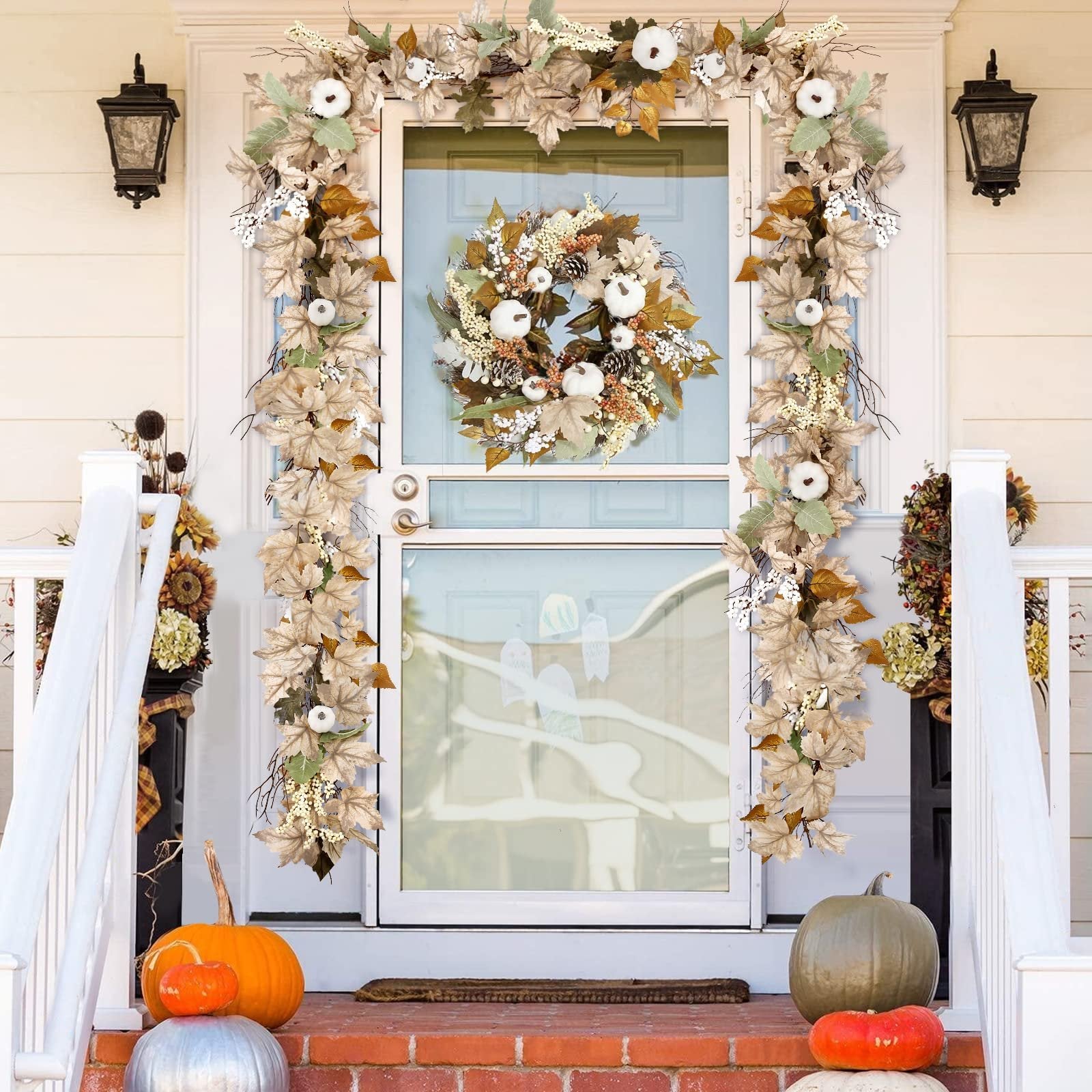 Autumn garland and wreath with pumpkins and maple leaves decorating a front door and porch