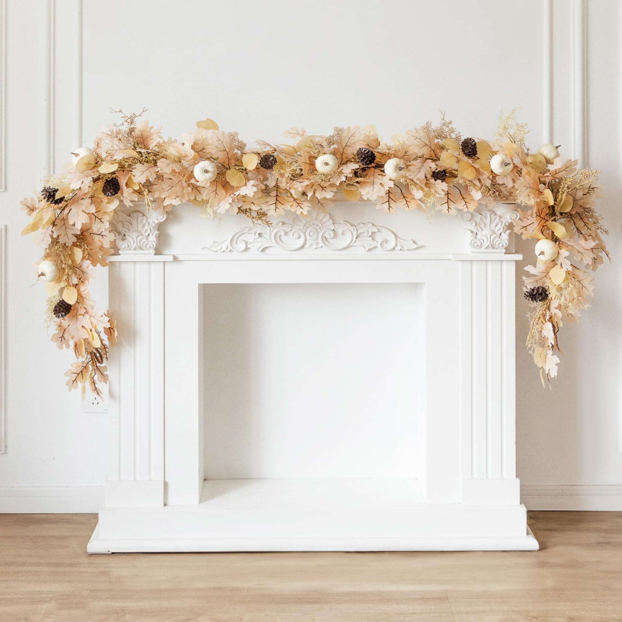 Boho fall garland with artificial pumpkins, pinecones, and maple leaves draped over a white fireplace mantel.