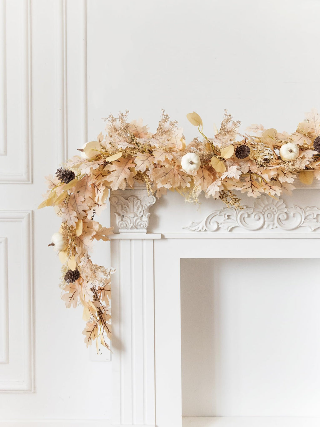 Boho fall garland with artificial leaves, mini pumpkins, and pinecones draped over a white fireplace mantel.