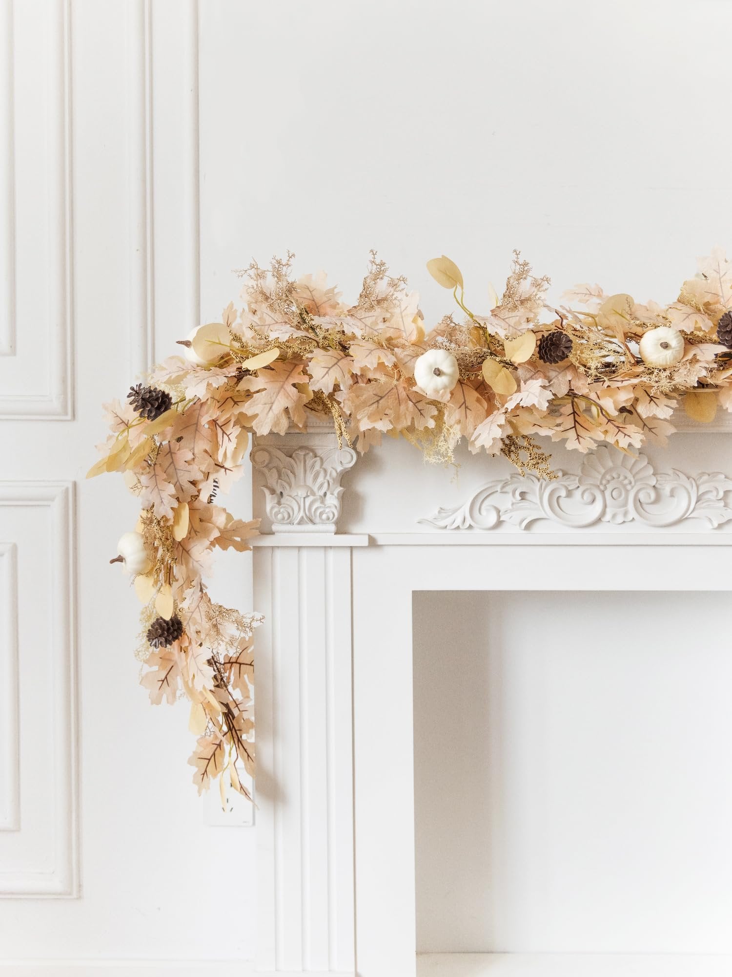 Boho fall garland with artificial leaves, mini pumpkins, and pinecones draped over a white fireplace mantel.