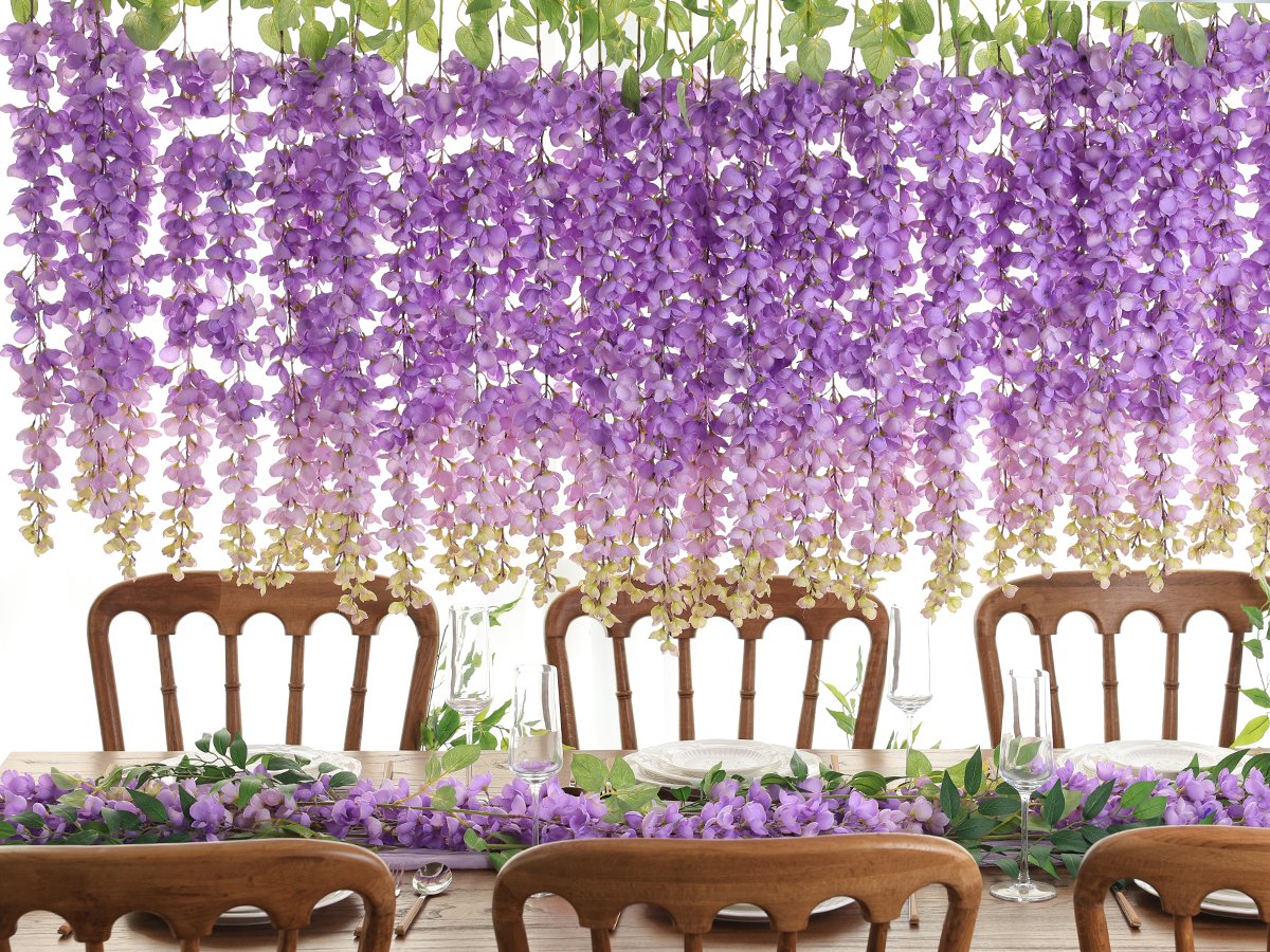 Purple wisteria hanging flowers draped over a wooden table set for a meal, with chairs visible.