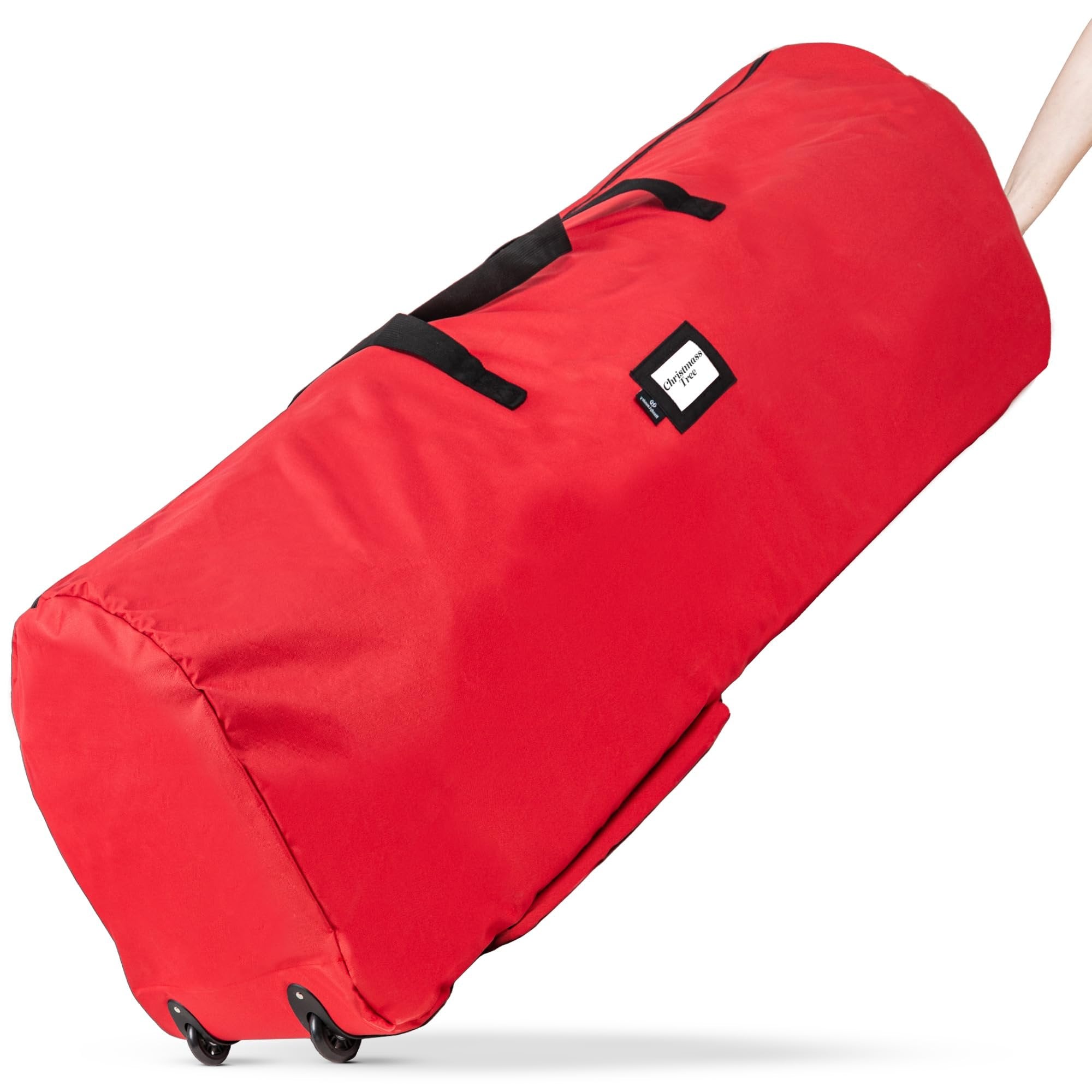 Red artificial Christmas tree storage bag with wheels and handles, shown at an angle with a hand pulling the handle.