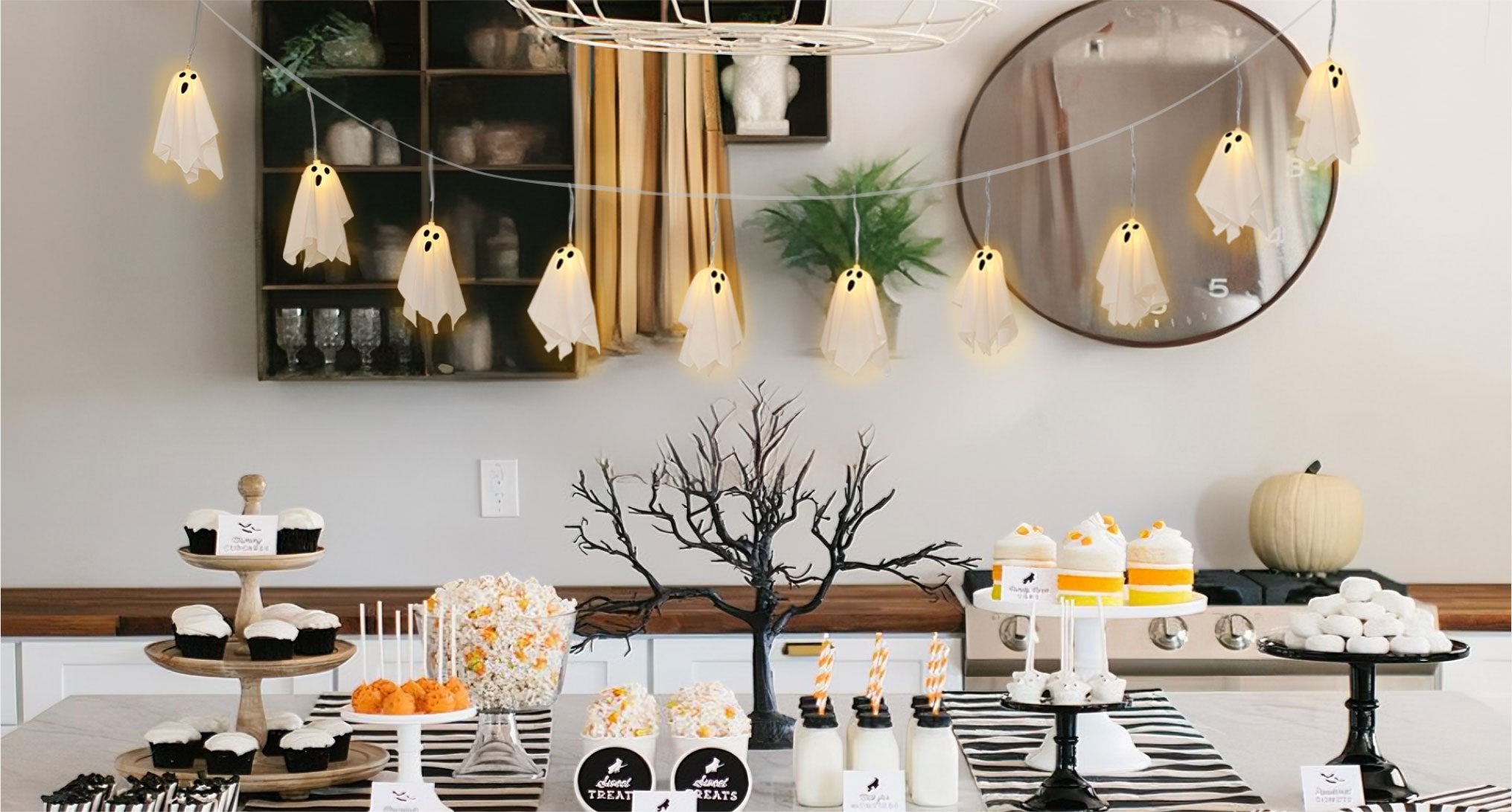 Halloween ghost string lights with 10 LED ghosts hanging over a party table with treats
